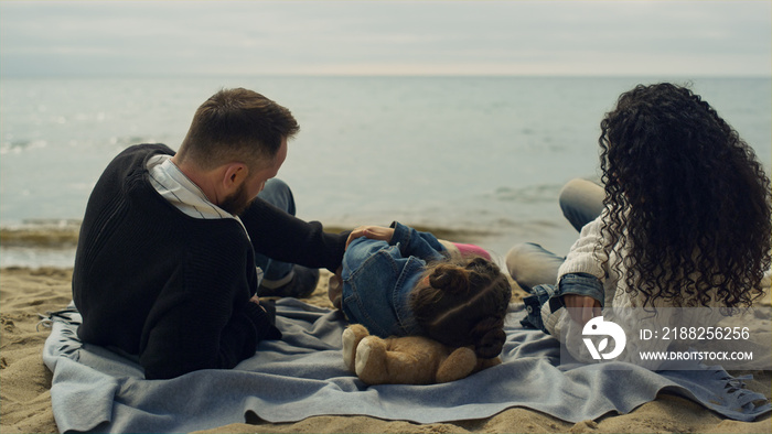 Parents child laying beach by sea shore nature. Happy family playing on picnic.