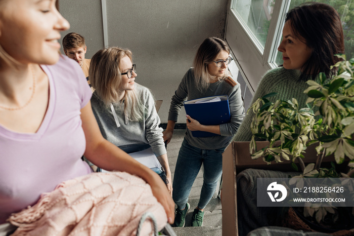 Smiling, foretaste, anticipating students carrying luggage on the stairs, talking while relocation. First year education