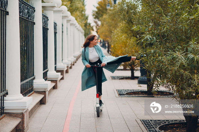 Young woman riding electric scooter in autumn city. Alternative commuter transportation.