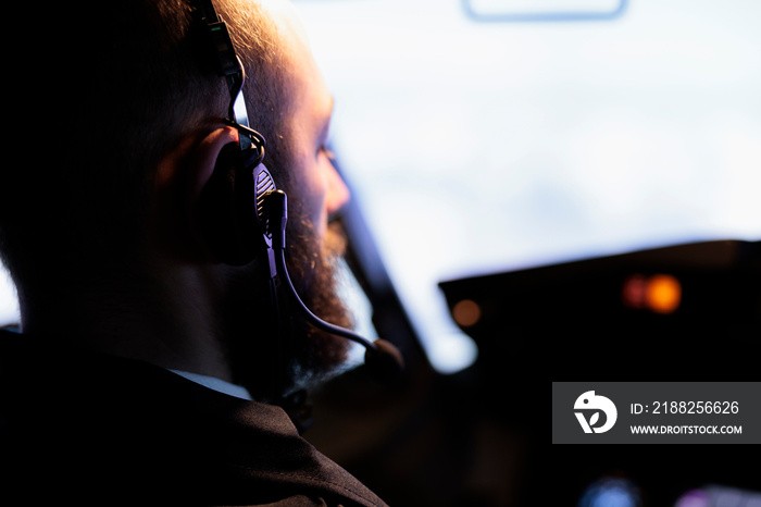 Male aviator looking through windscreen to fly aircraft, starting power engine and pushing dashboiard command buttons to takeoff. Airliner flying airplane with radar compass navigation. Close up.