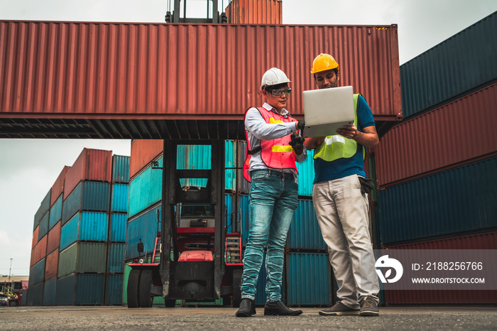 Industrial worker works with co-worker at overseas shipping container yard . Logistics supply chain management and international goods export concept .