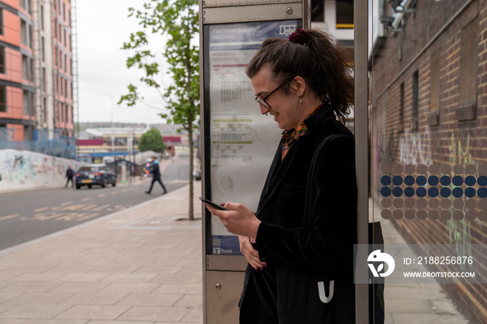 Young man using phone while waiting at bus stop