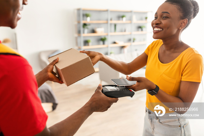 African American Customer Woman Paying Delivery Guy Using Phone Indoors