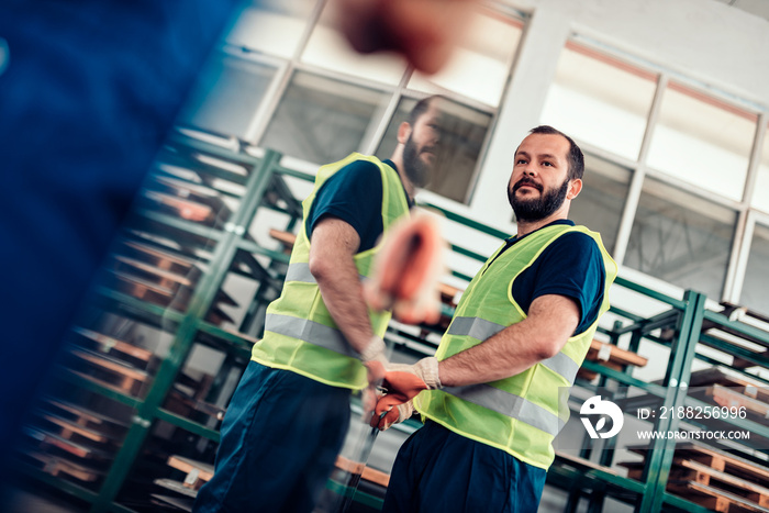 Warehouse workers carrying stainless steel inox sheet metal in factory