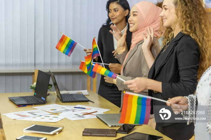 Five business women from different ethnic races and cultures express support for LGBT with flags in an office