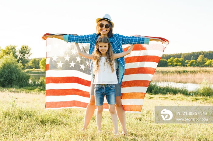 Positive portrait of mom and daughter with American flag. Nature background, rural landscape