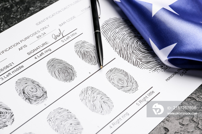 Paper sheet with finger prints, pen and flag of USA on dark background, closeup