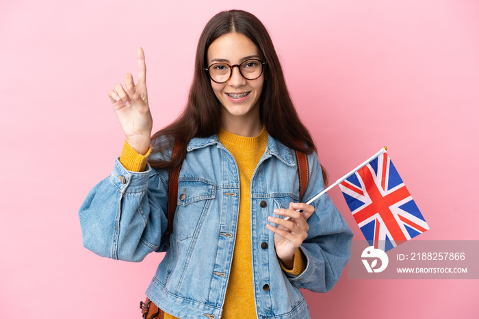 Young French girl holding an United Kingdom flag isolated on pink background pointing up a great idea