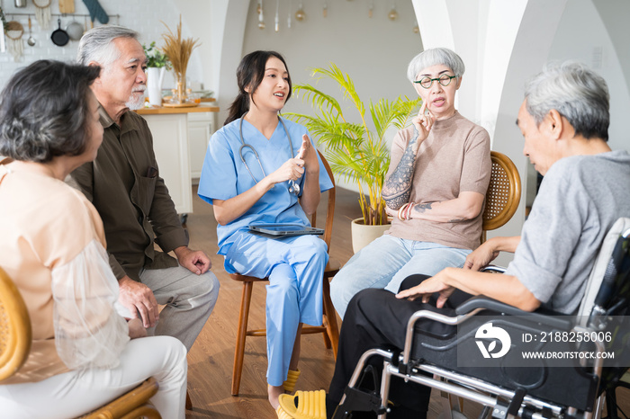 Group of Asian senior people sit in a circle in a nursing home and listen to nurse during a group elderly therapy session.