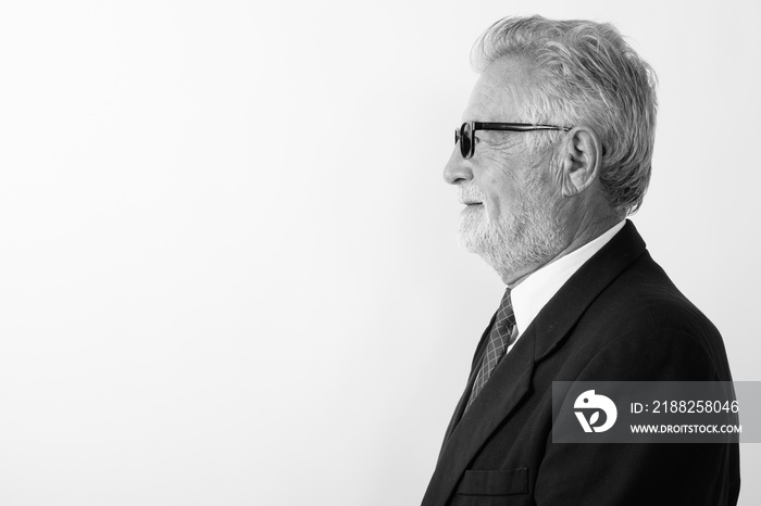 Profile view of happy senior bearded businessman smiling while wearing eyeglasses against white background