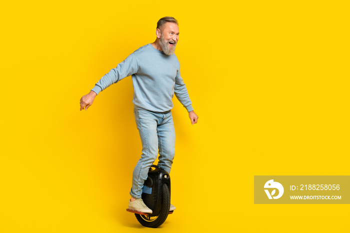 Full body photo of overjoyed aged man ride gyro wheel look empty space isolated on yellow color background