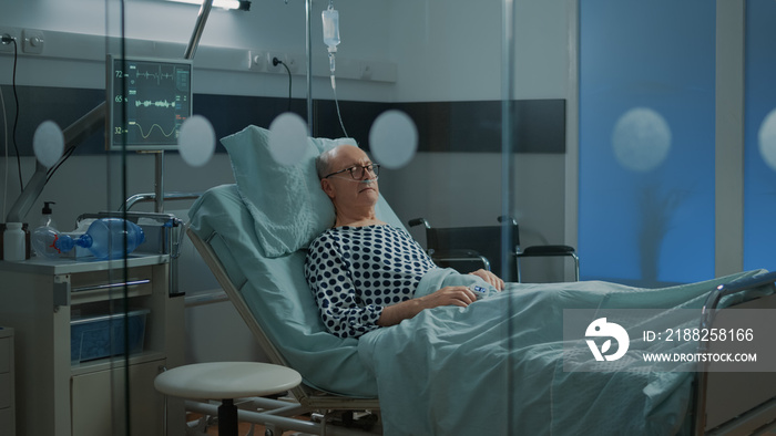 Sick patient sleeping in hospital ward bed at health facility with nasal oxygen tube for breathing problems. Old man with disease waiting for medical treatment to recover from illness