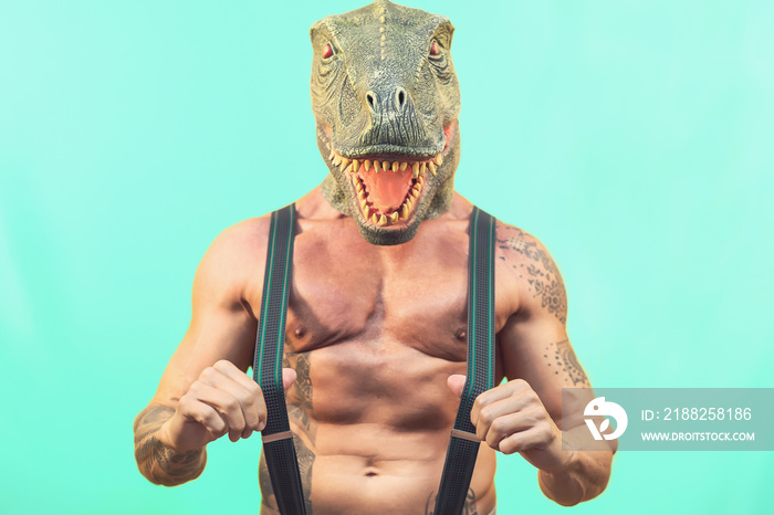 Fit senior man wearing t-rex dinosaur mask - Crazy hipster guy having fun celebrating masquerade carnival holidays - Absurd and surreal funny concept - Aquamarine background