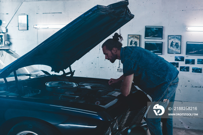 Attractive Caucasian man carrying out maintenance of his old vintage retro car