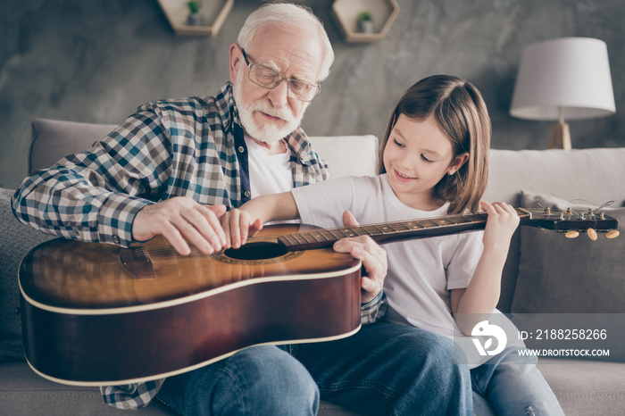 Photo of funny aged old grandpa little pretty granddaughter holding playing guitar teaching small princess bonding spend stay home quarantine useful time modern interior living room indoors