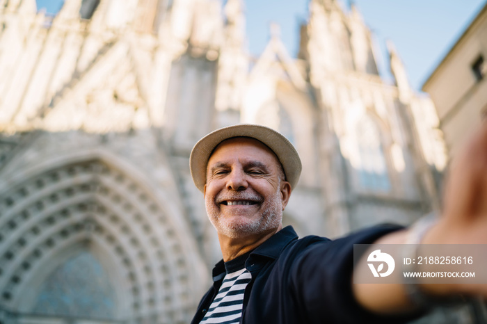 Cheerful man taking selfie against historical building