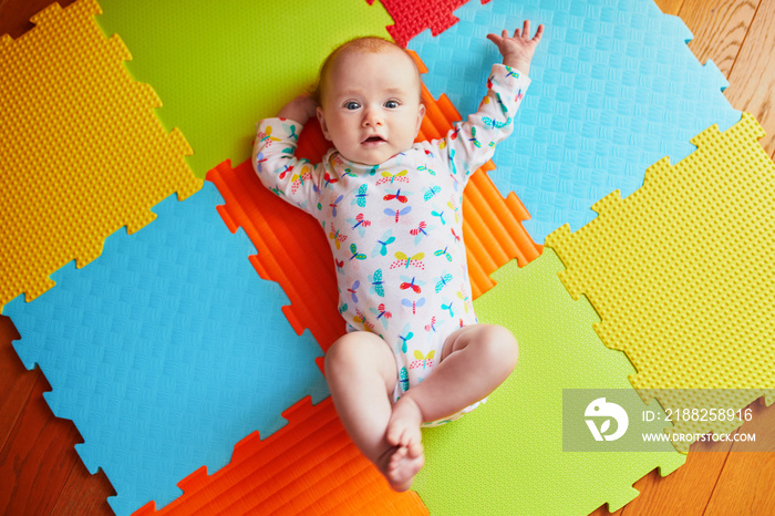 4 months old baby girl lying on colorful play mat