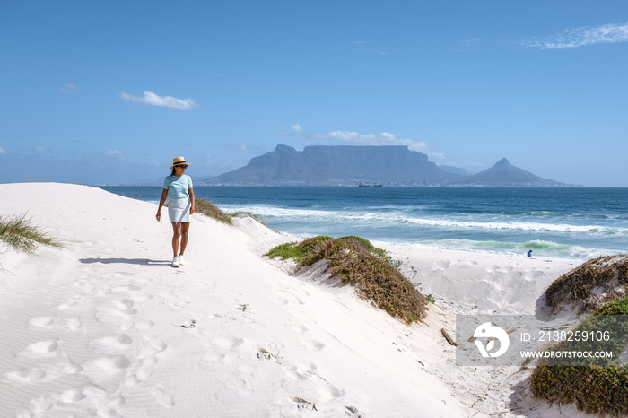 Bloubergstrand Cape Town South Africa on a bright summer day, Blouberg beach, withe powder sand and blue ocean. woman wiht hat walking at the beach