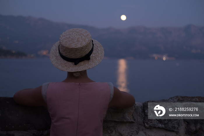 Girl watching the ocean / sea horizon with a Moon rise.