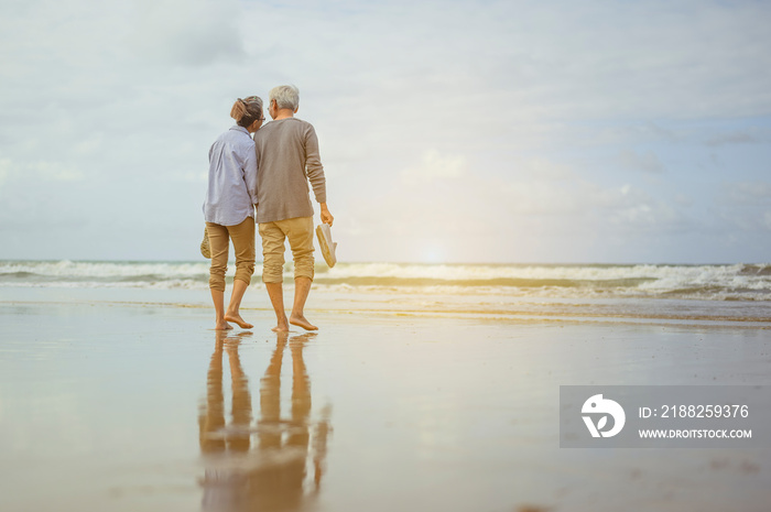 Senior couple walking on the beach holding hands at sunrise, plan life insurance at retirement concept.