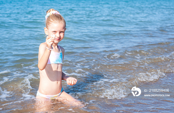 Little girl playing on the beach by the sea