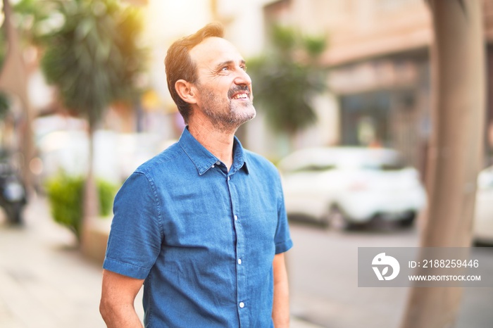 Middle age handsome man standing on the street smiling