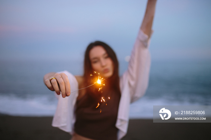 Let’s sparkle things up. Young woman celebrating with bengal lights at the beach.