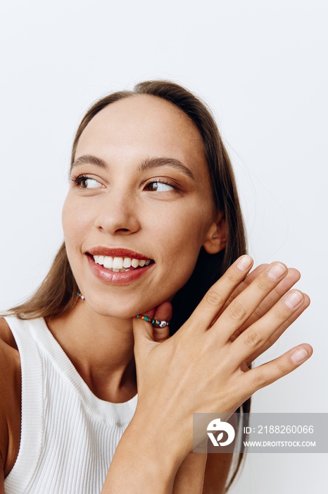 Portrait of a young beautiful woman with tanned skin model on a white background in a white T-shirt with a chain around her neck