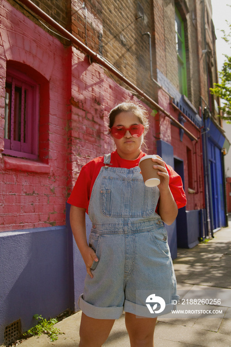 Confident young woman with Down Syndrome in an urban environment holding a coffee-to-go