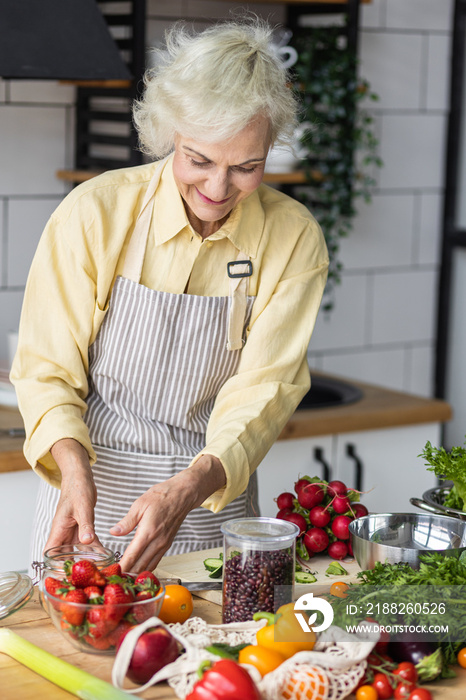 Senior woman pensioner with a glass of clean water in her kitchen. Concept of healthy eating for mature female, vegetarian diet, detox, vitamin salad. Health care and healthy lifestyle