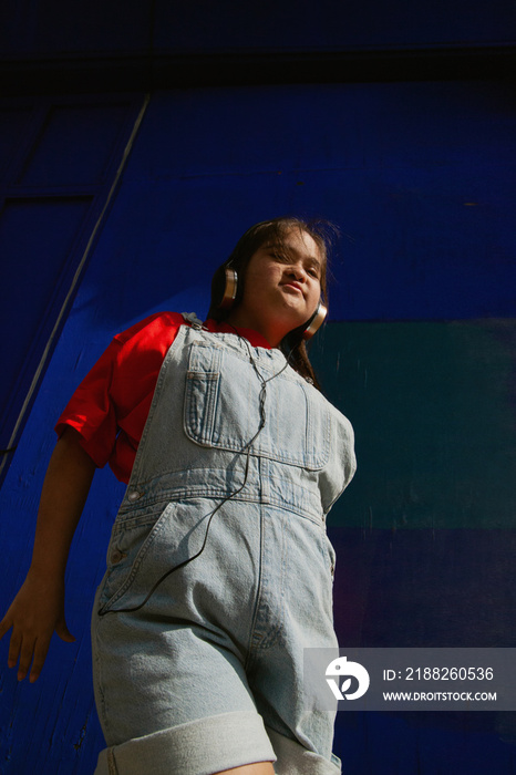 Young curvy woman with Down Syndrome dancing in the sun with headphones