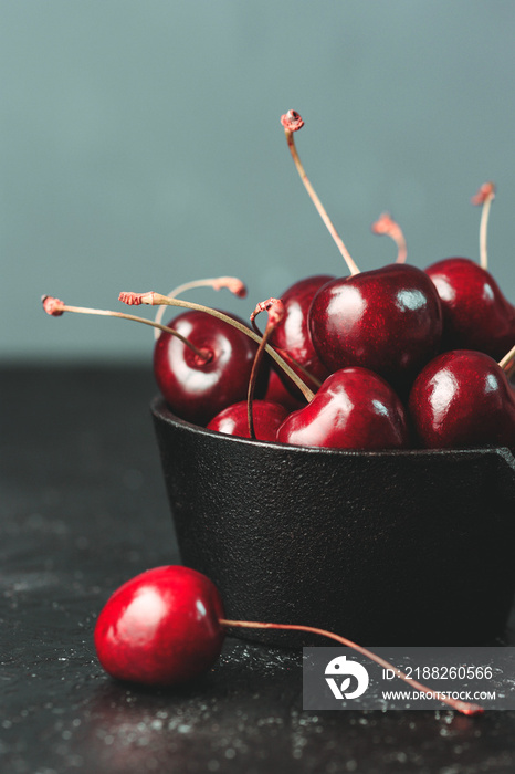 Fresh ruby cherries on black background. Dark moody close up still life