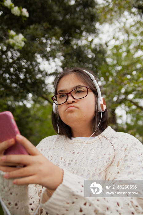 Young mid-sized woman with Down syndrome listening to music outdoors