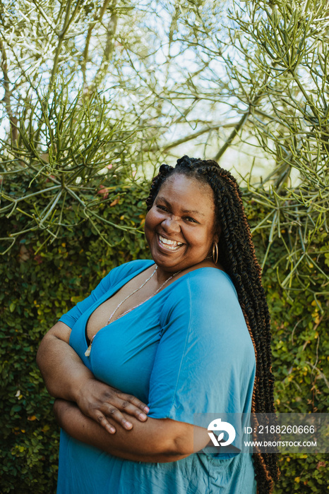 portrait of a plus size African American woman standing in front of plants laughing