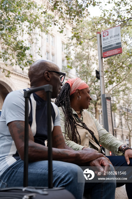 UK, London, Happy mature couple sitting at bus stop