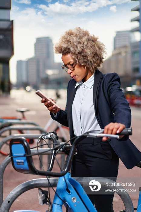 Young afro woman renting bicycle in bike sharing city service