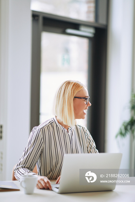 Young businesswoman laughing while working on a laptop