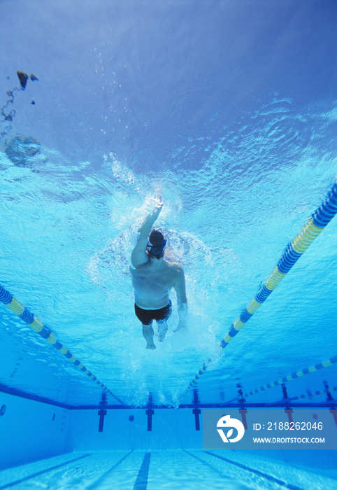 Underwater shot of young male athlete doing backstroke in swimming pool