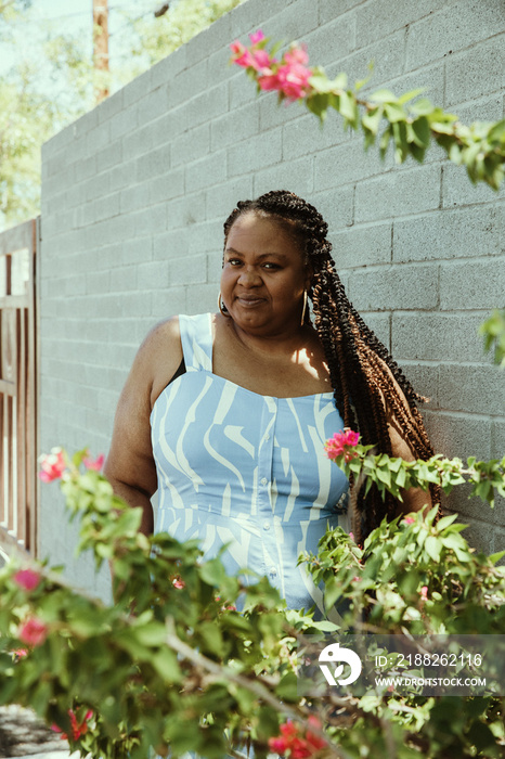 Plus size afro latinx Haitian American woman stands against wall looking at camera