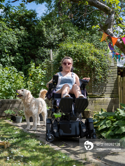 Woman in electric wheelchair with dog in back yard