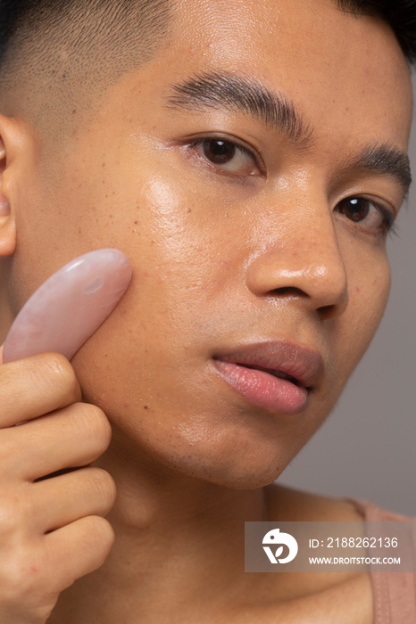 Close-up of person using rose quartz guasha