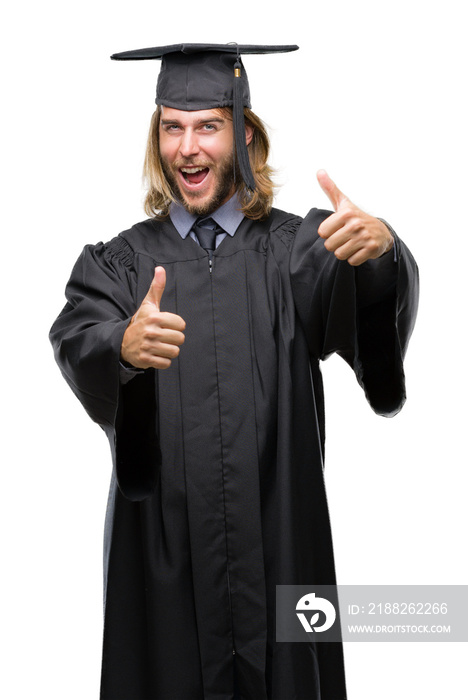 Young handsome graduated man with long hair over isolated background approving doing positive gesture with hand, thumbs up smiling and happy for success. Looking at the camera, winner gesture.