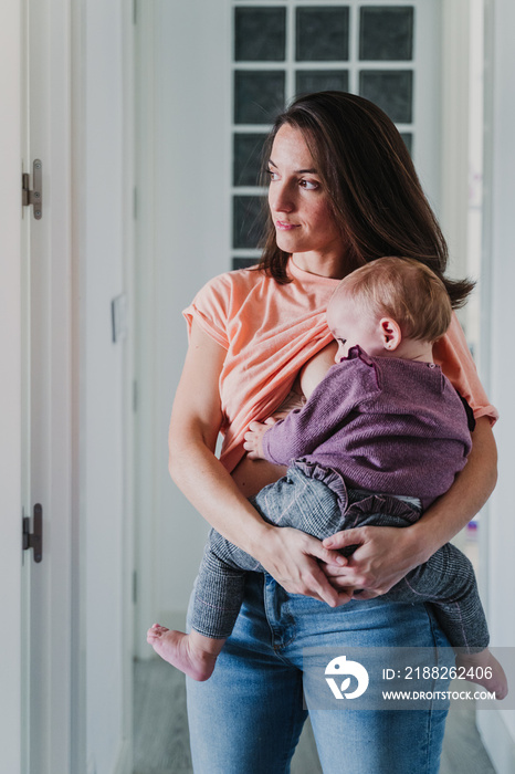 young mother at home breast feeding her adorable one year old baby girl. family time