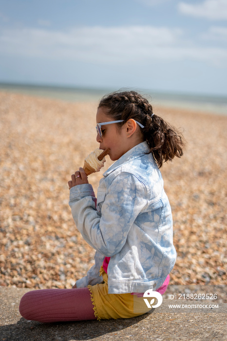 Girl (8-9) eating ice cream on beach