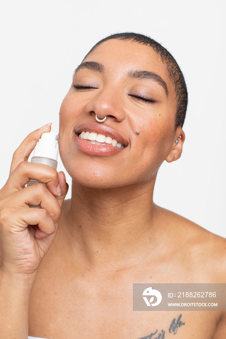 Studio portrait of smiling woman applying face serum