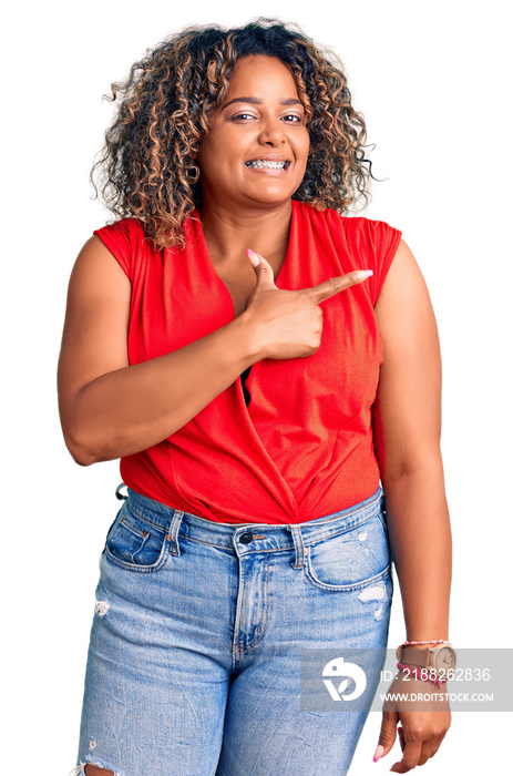 Young african american plus size woman wearing casual style with sleeveless shirt cheerful with a smile on face pointing with hand and finger up to the side with happy and natural expression