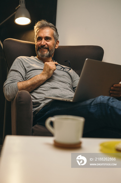 man using laptop relaxed in his sofa at his apartment