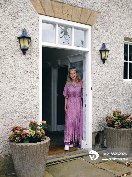 Smiling mature woman standing at front door