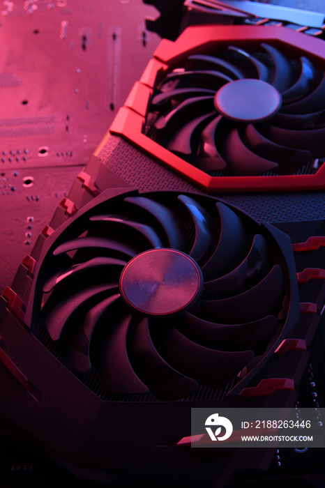 Computer game graphics card, videocard with two coolers on circuit board ,motherboard background. Close-up. With red-blue lighting