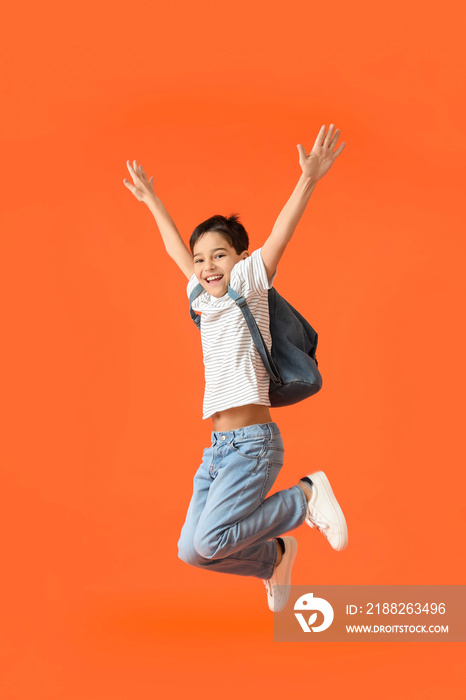 Jumping little schoolboy on color background